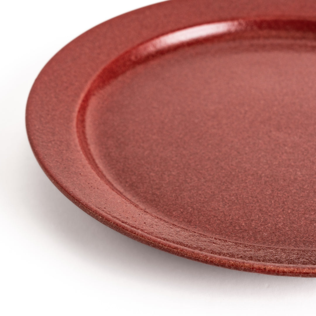 Red ceramic dinner plate with a glossy finish, providing a bold and vibrant accent to any dining arrangement.