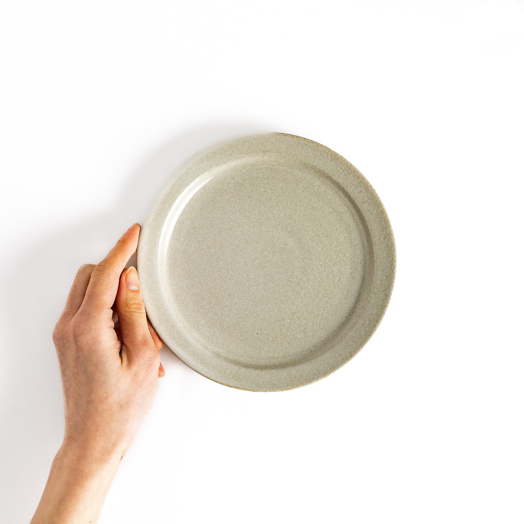 Hand holding a white salad plate, showcasing its size and versatile design ideal for salads and sides.