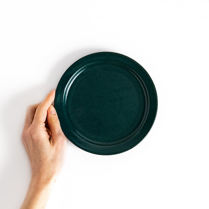 Hand holding a green salad plate, showcasing its size and versatile design ideal for salads and sides.