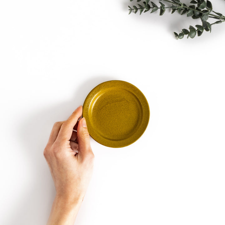 Hand-held yellow ceramic sauce dish showcasing its sleek glossy surface and compact size, perfect for everyday use.