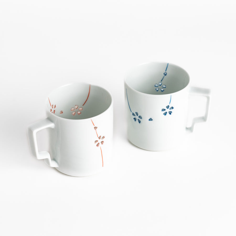 Pair of unique ceramic mugs featuring delicate floral designs in red and blue, perfect for adding a touch of elegance to your morning coffee.