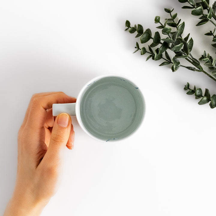 Elegant white ceramic mug with a subtle blue floral pattern, ideal for enjoying your favorite hot beverages.