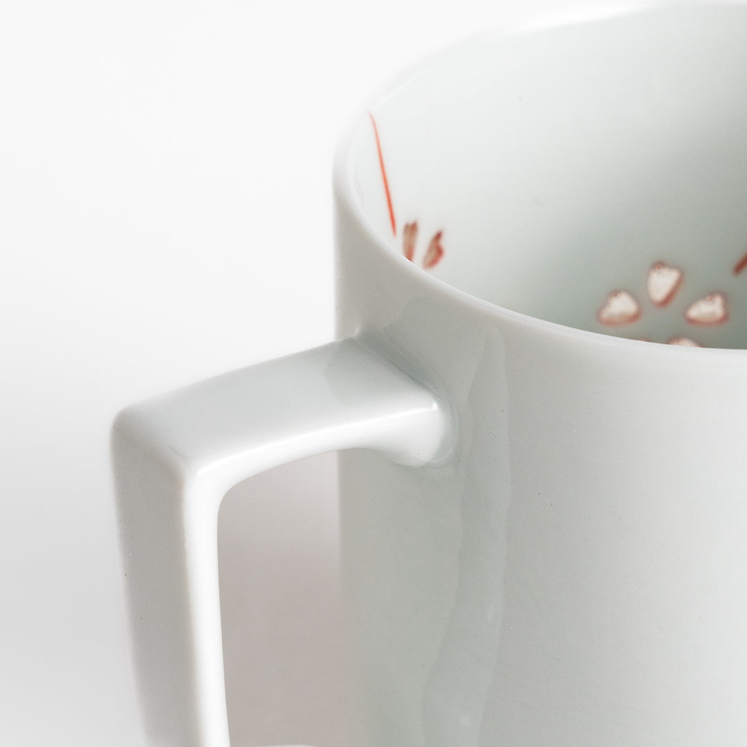 Elegant white ceramic mug with a subtle red floral pattern, ideal for enjoying your favorite hot beverages.