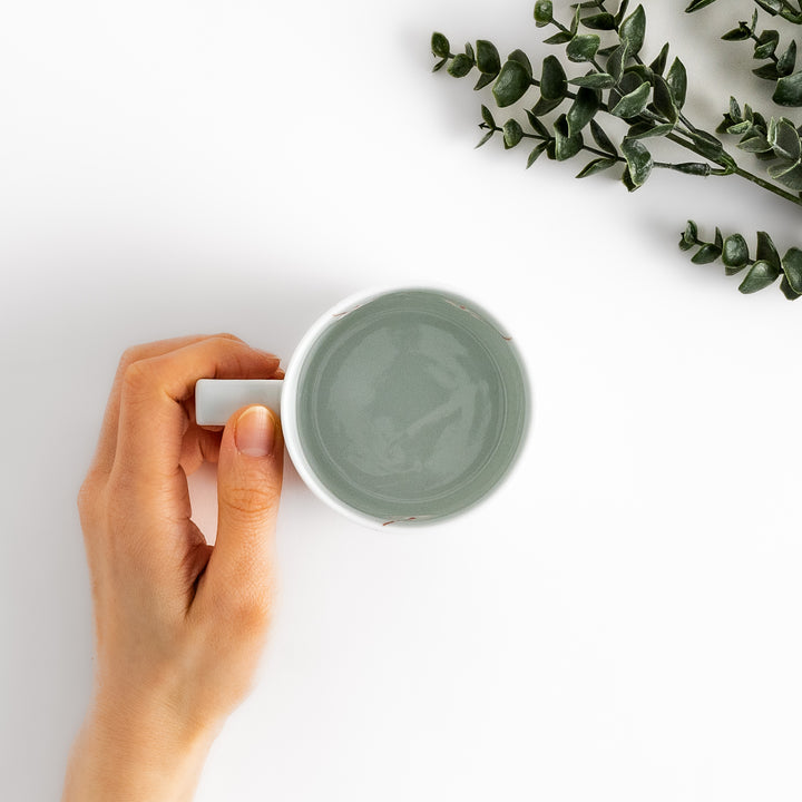 Elegant white ceramic mug with a subtle red floral pattern, ideal for enjoying your favorite hot beverages.