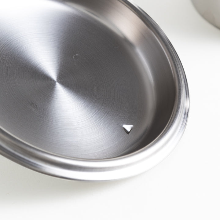 A metal pan placed on a clean white background, showcasing its shiny surface and sleek design.