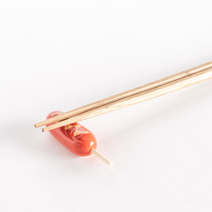 Close-up of a corn dog chopsticks rest with wooden chopsticks placed across it.