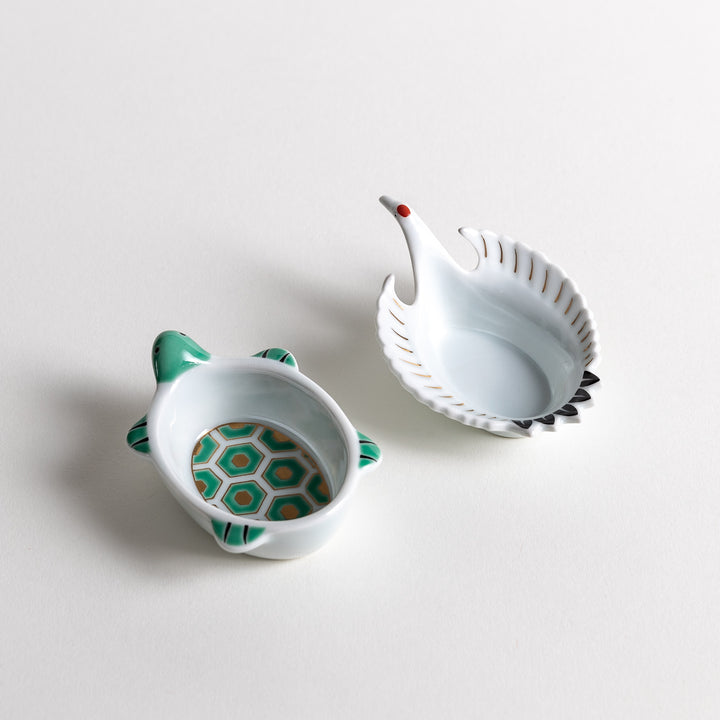 A turtle-shaped dish with a hexagonal pattern inside, paired with a crane-shaped dish featuring a delicate wing design, both elegantly placed side by side.