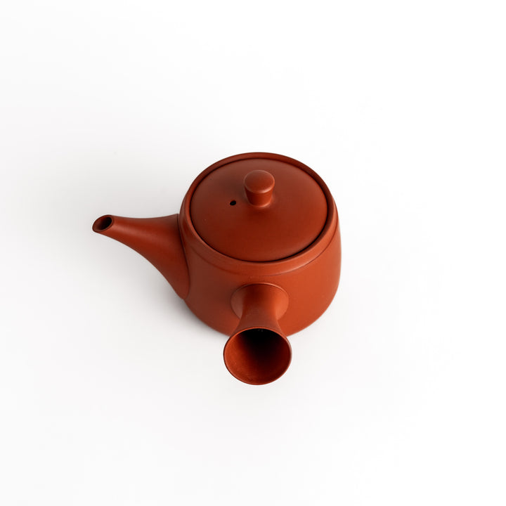 Slightly angled view of the teapot, highlighting its sleek curves and rich crimson color.