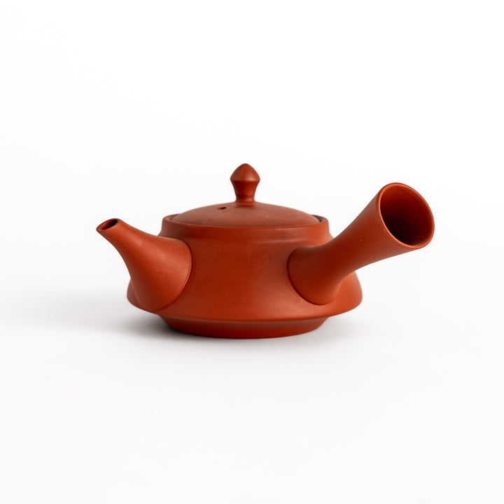 Elegant crimson teapot with a smooth matte finish and a rounded spout, designed for serving tea with a touch of sophistication.