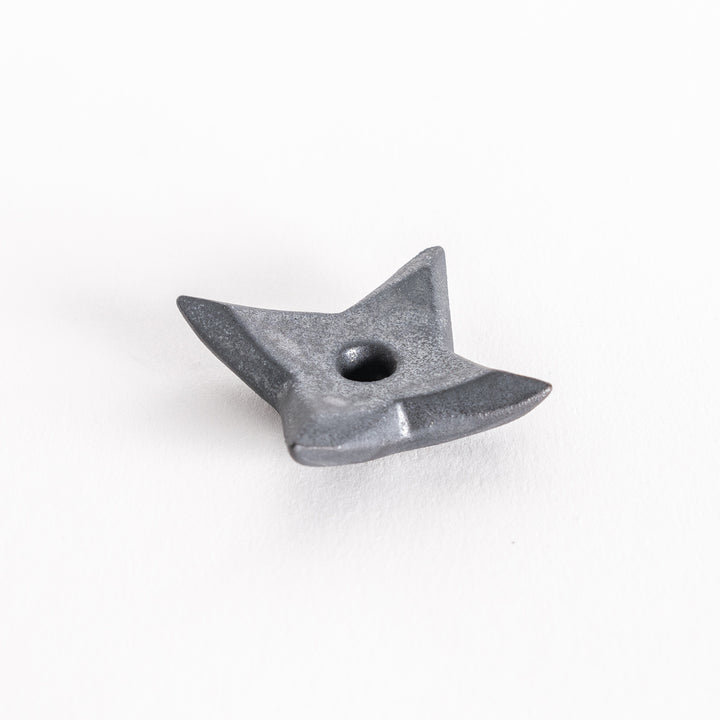 Slightly angled view of a metallic black ninja star-shaped chopstick rest, showcasing its pointed edges and smooth surface.