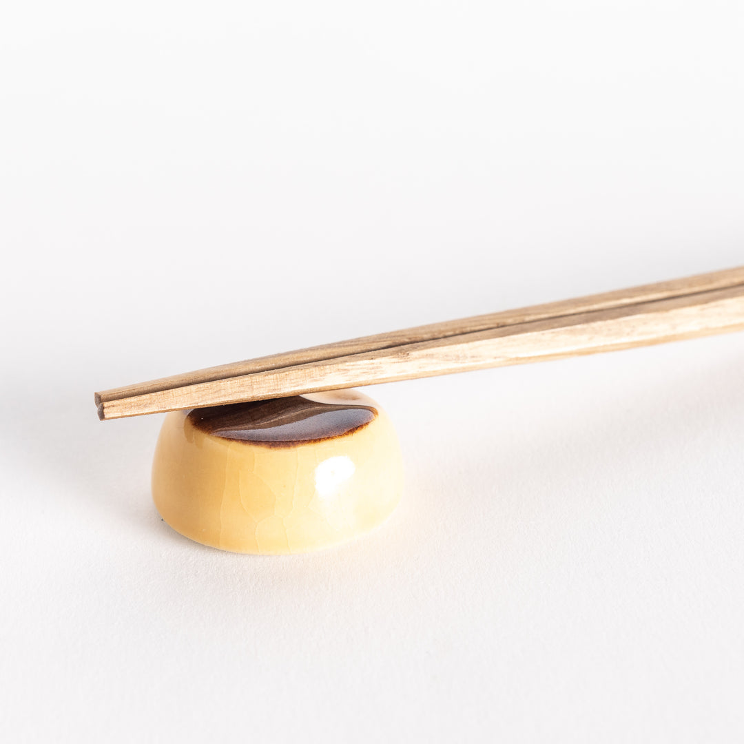 Close-up of the custard pudding chopsticks rest with chopsticks placed on top, highlighting its smooth, glossy details.