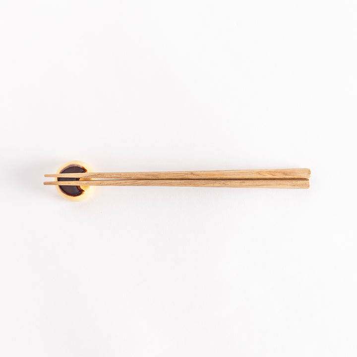 The custard pudding chopsticks rest with chopsticks resting across it, showcasing its playful pudding design.