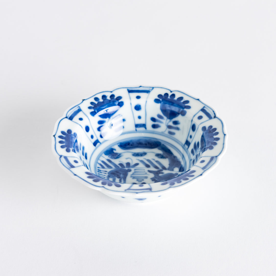 A dessert bowl with a scalloped edge, decorated in blue with pastoral scenes of deer and landscape motifs.