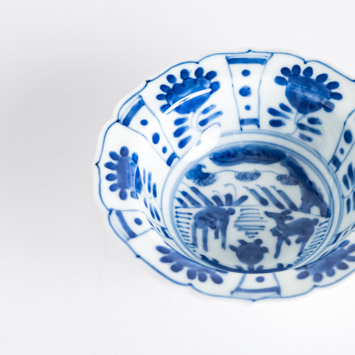 A dessert bowl with a scalloped edge, decorated in blue with pastoral scenes of deer and landscape motifs.