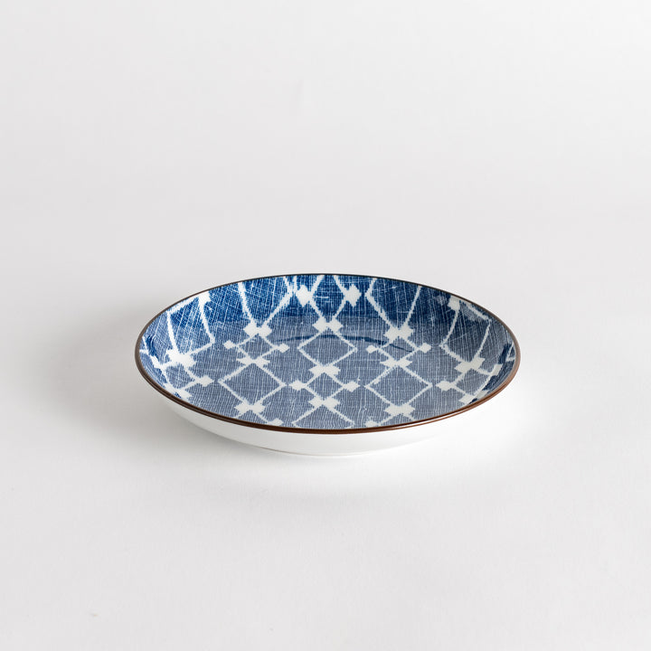 A round dessert plate featuring a bold blue and white lattice pattern.