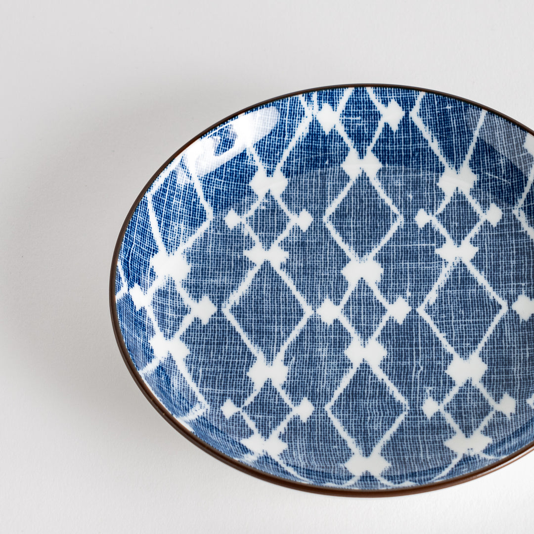 A round dessert plate featuring a bold blue and white lattice pattern.