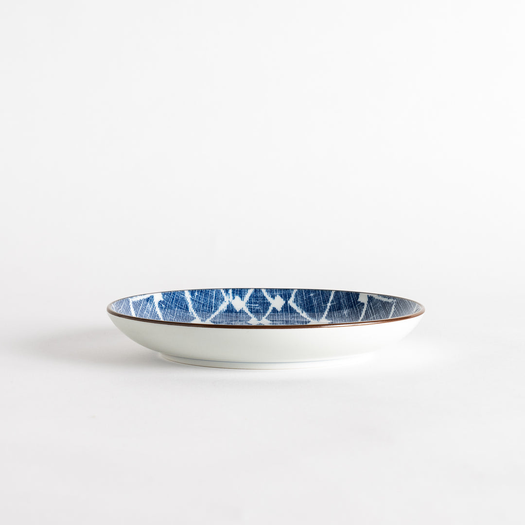 A round dessert plate featuring a bold blue and white lattice pattern.