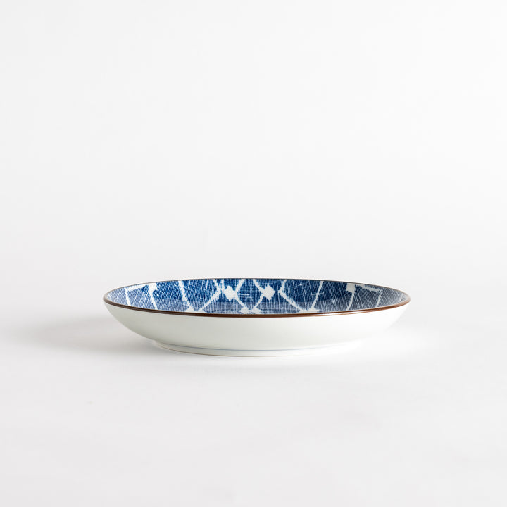 A round dessert plate featuring a bold blue and white lattice pattern.