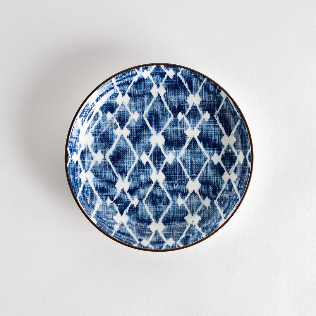 A round dessert plate featuring a bold blue and white lattice pattern.