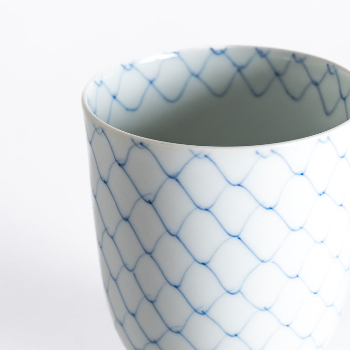 Close-up of the tea cup’s delicate blue diamond pattern against the white porcelain surface.