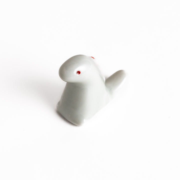 Whimsical white ceramic chopstick rest shaped like a cute dinosaur, adding a playful touch to your table setting and keeping your chopsticks clean.