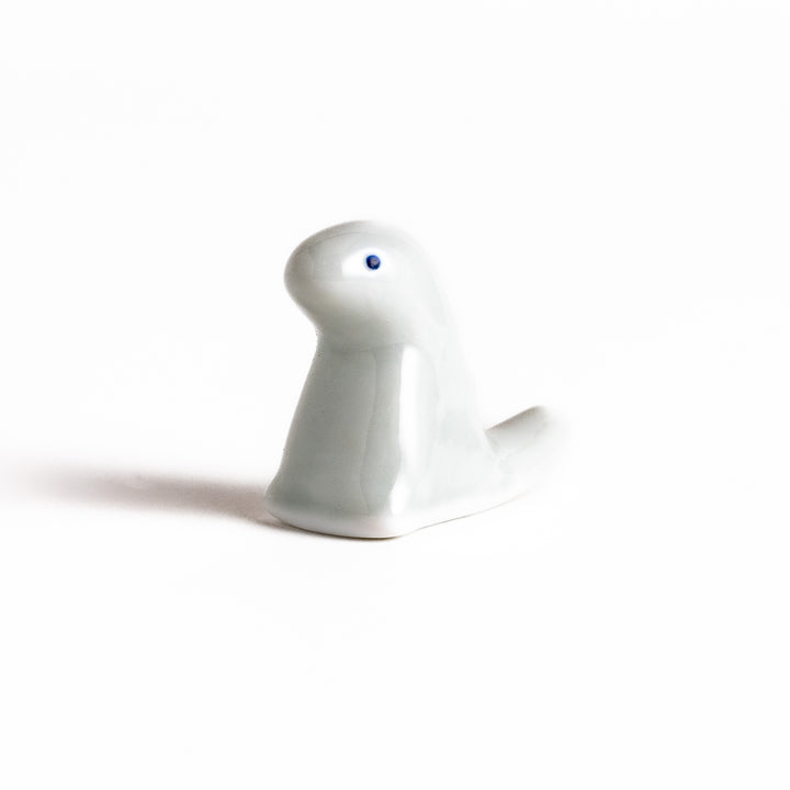 Whimsical white ceramic chopstick rest shaped like a cute dinosaur, adding a playful touch to your table setting and keeping your chopsticks clean.