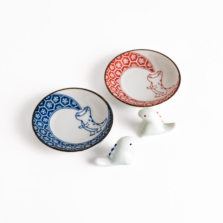 Two small sauce plates with a cute dinosaur design, paired with matching dinosaur chopstick rests, adding a playful touch to any meal.