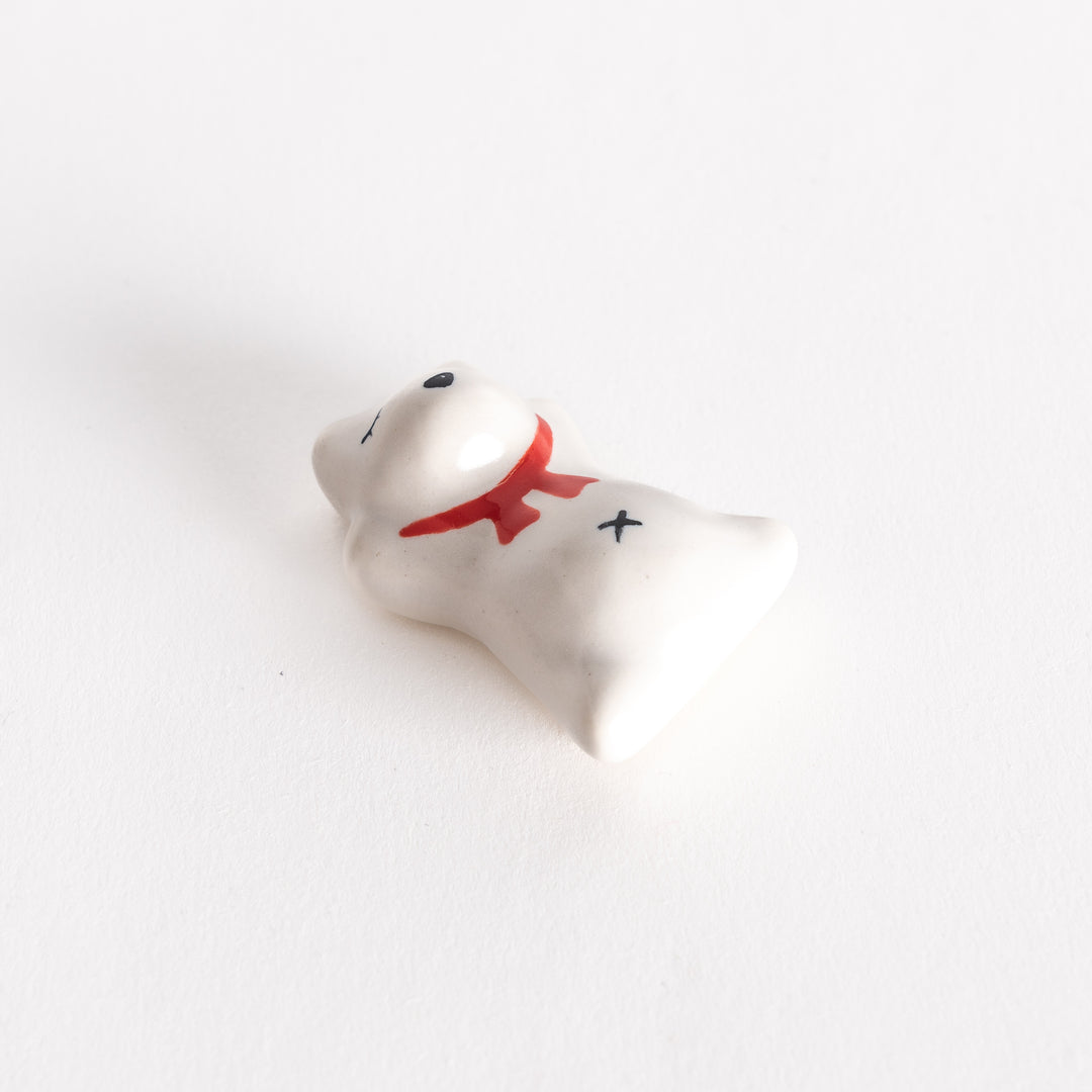 A slightly angled view of the dog-shaped ceramic chopstick rest, emphasizing its red scarf and whimsical sleeping expression.