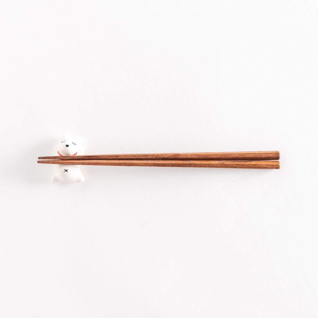 A wide view of the dog-shaped chopstick rest with chopsticks placed across its back, showcasing the playful design.