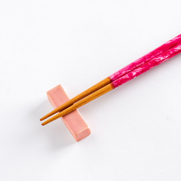 Close-up of pink chopstick tips with a subtle sparkle, resting on a pink ceramic holder.