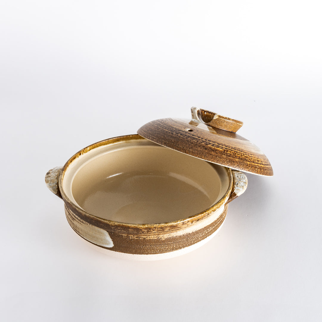 Donabe with the lid slightly shifted, revealing the textured brown interior and sturdy handles.