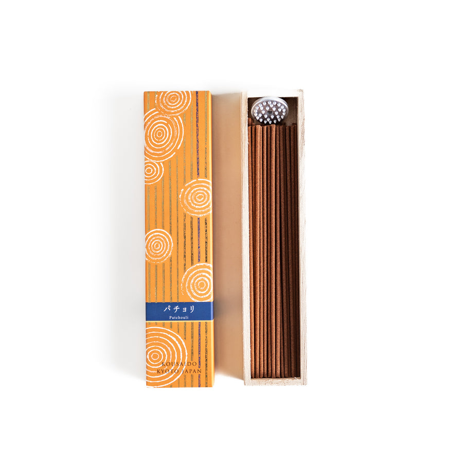 Earthy Patchouli Incense in a light wooden box with warm brown sticks, elegantly packaged in an orange design featuring white circular patterns, evoking a rich and grounding aroma.