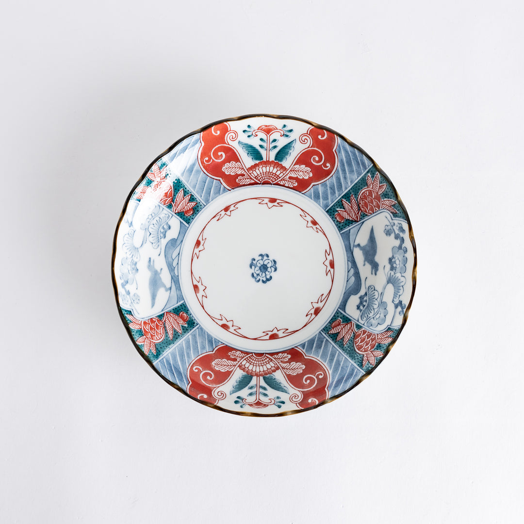 Top view of a decorative plate featuring intricate designs in red, blue, and green colors with floral and dinosaur motifs.