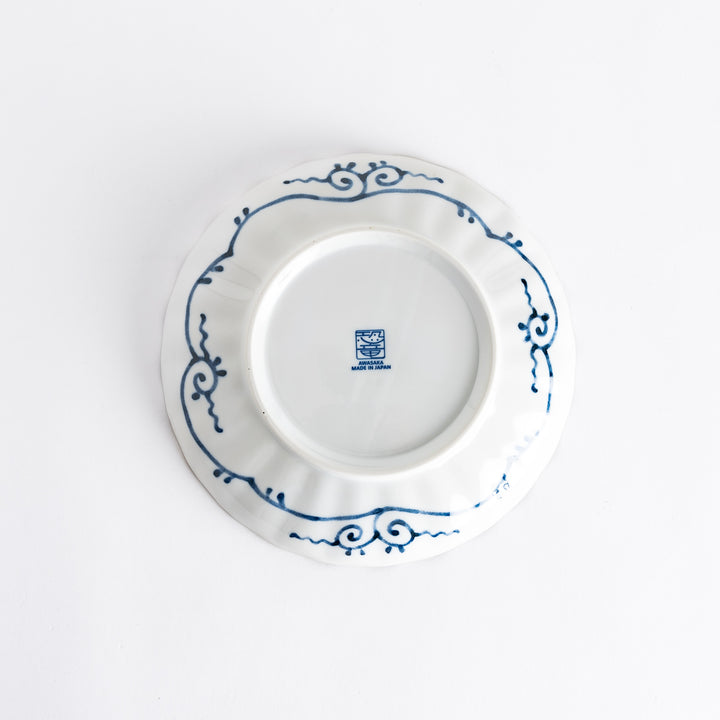 Bottom view of the decorative plate, displaying the maker's mark and decorative swirls in blue on a white background.