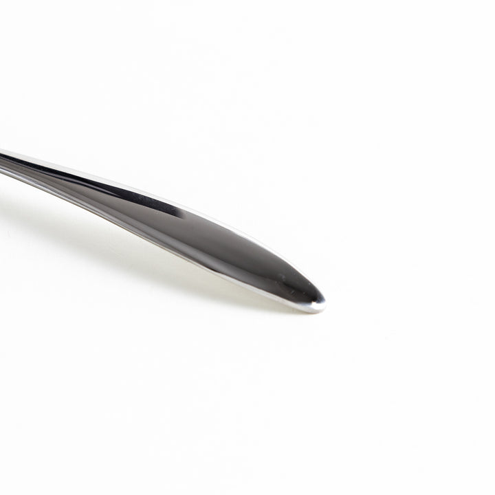 Close-up of a stainless steel fork’s handle, showing its smooth, polished finish.