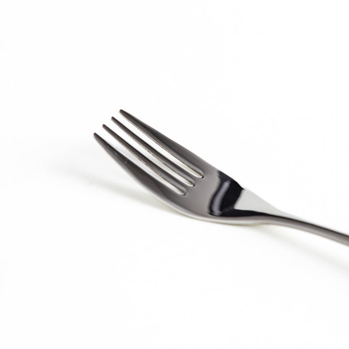 Close-up of a stainless steel fork's prongs and handle on a white background.