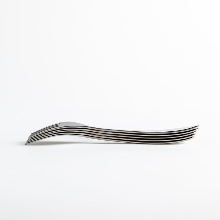 Stacked stainless steel forks from a low angle, emphasizing their uniform design.