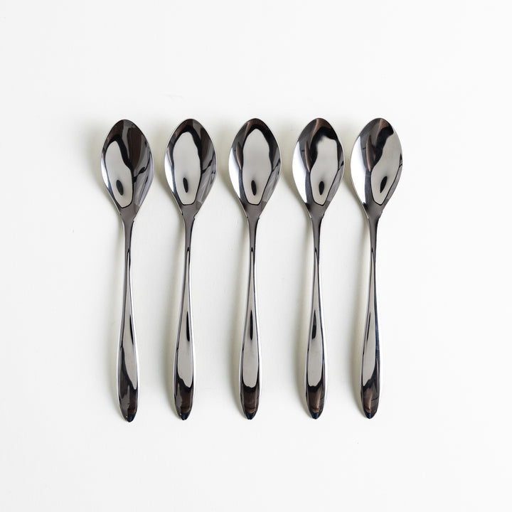 Five elegant stainless steel spoons arranged neatly in a row with polished surfaces reflecting light.