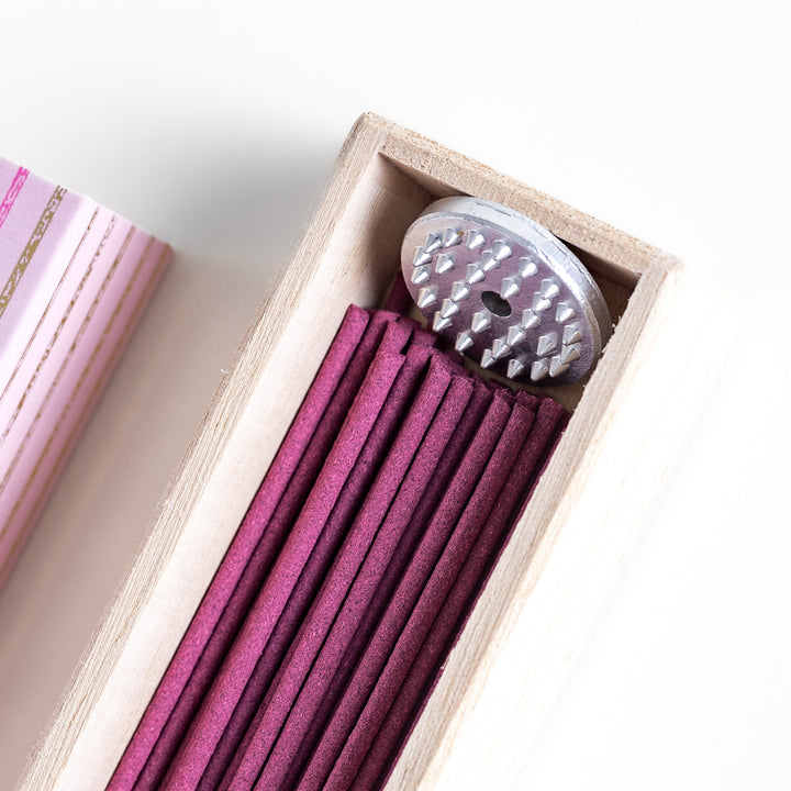 Elegant Sakura Incense in a light wooden box with soft pink sticks, elegantly packaged in a delicate pink design featuring white circular patterns, evoking the gentle aroma of cherry blossoms.