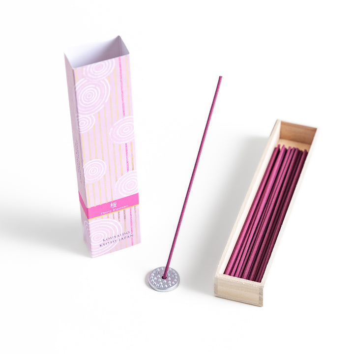 Elegant Sakura Incense in a light wooden box with soft pink sticks, elegantly packaged in a delicate pink design featuring white circular patterns, evoking the gentle aroma of cherry blossoms.