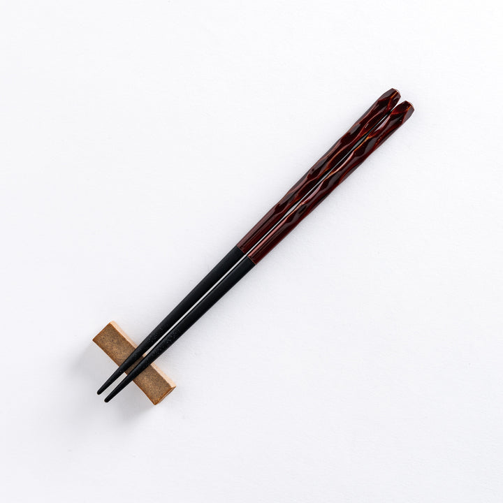 Ember color chopstick resting on a chopstick rest, highlighting its warm, rich hue and intricate design.