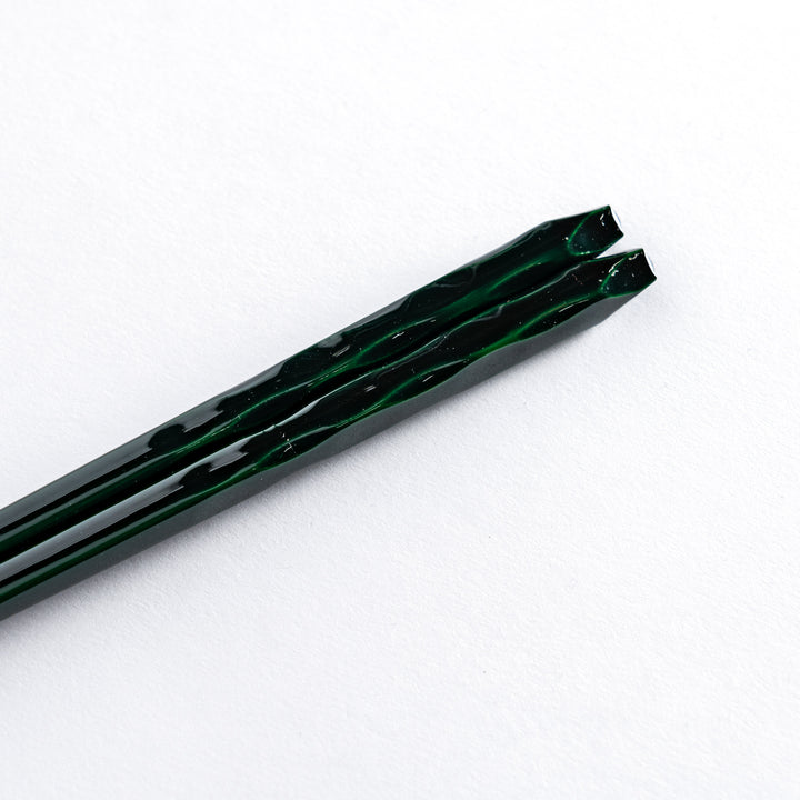 Close-up of the handle of the Forest color chopstick, highlighting the detailed carving and deep, earthy green tones.