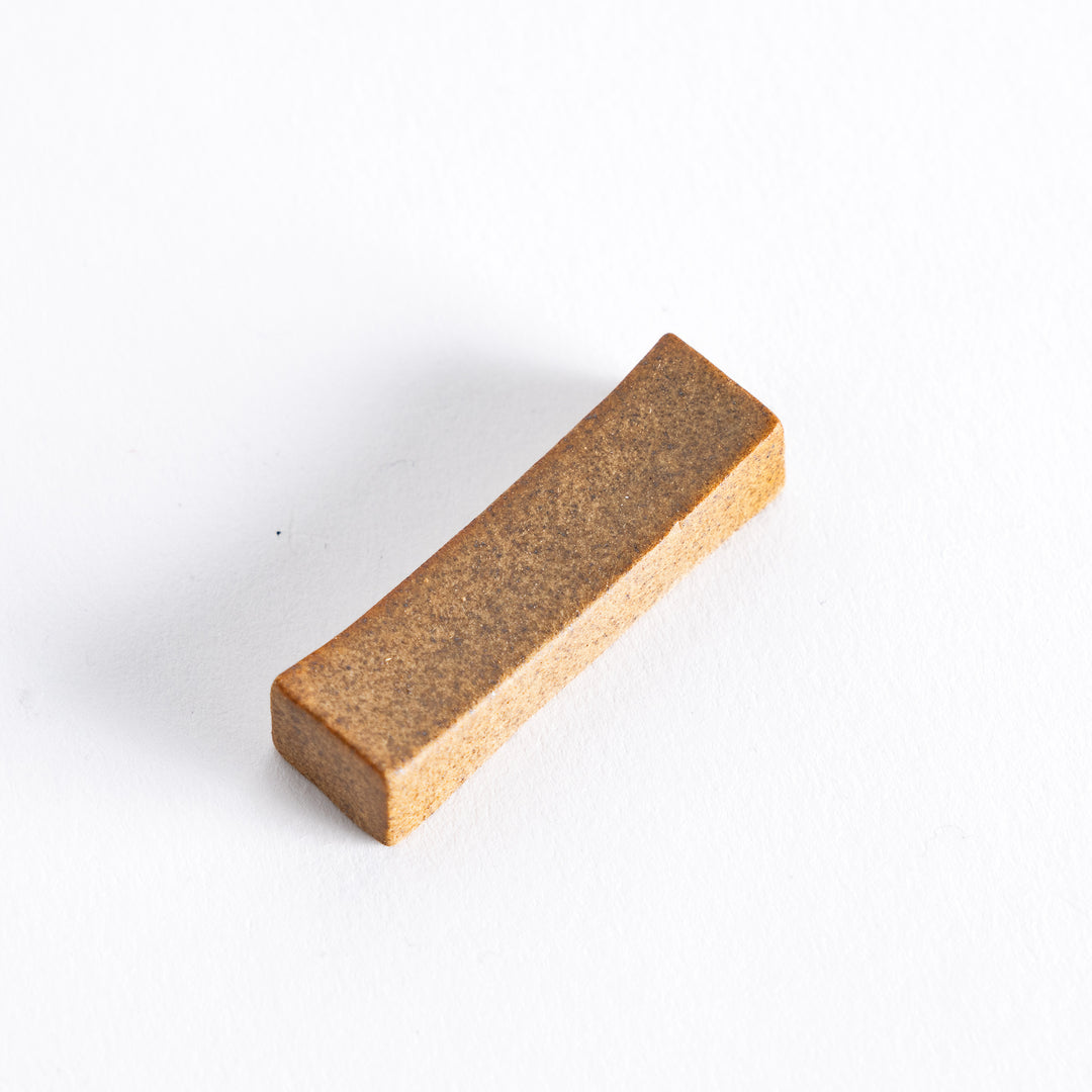 An earthy brown chopstick rest, showcasing its smooth texture and simple yet elegant design.