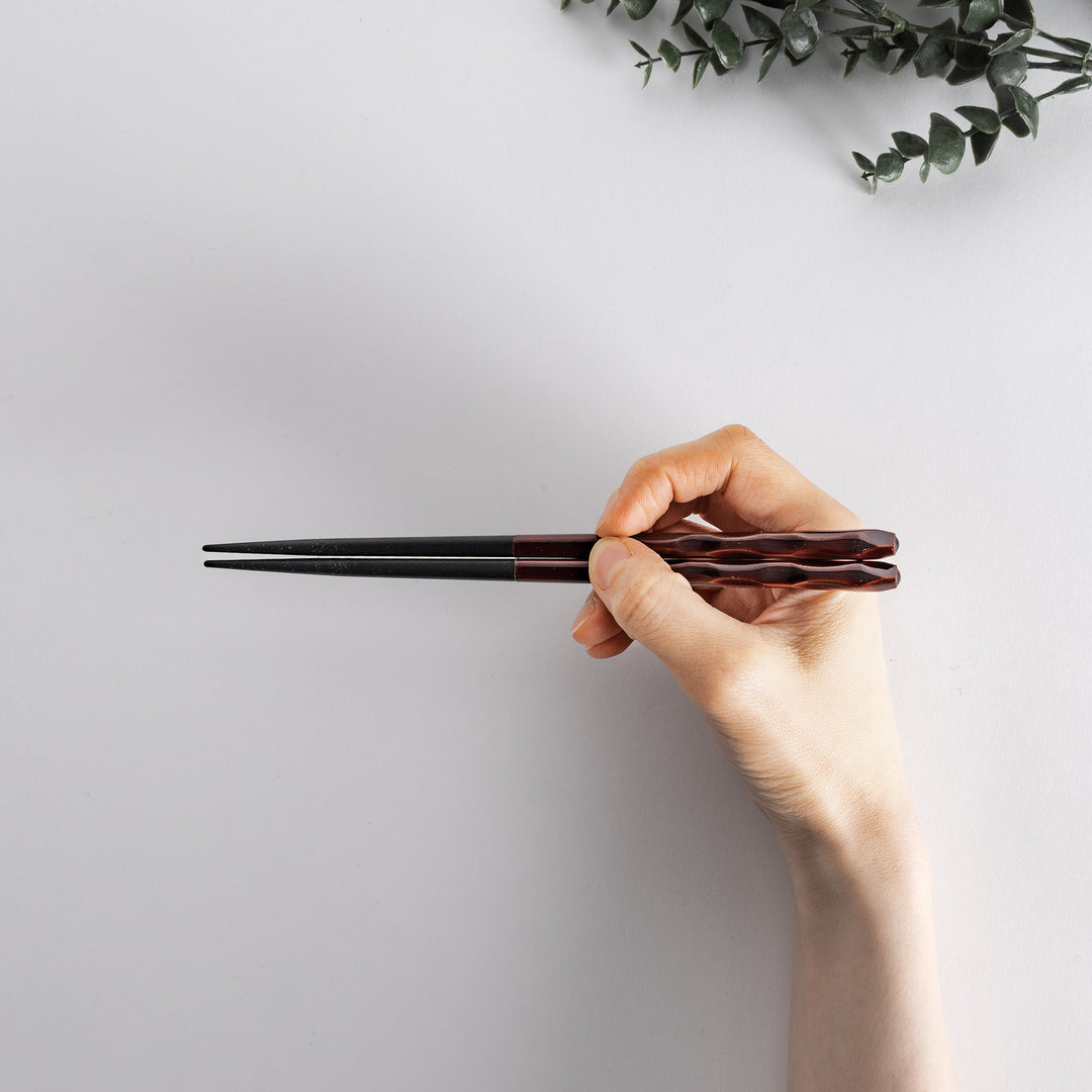 Ember color chopstick held in hand, displaying the detailed design.