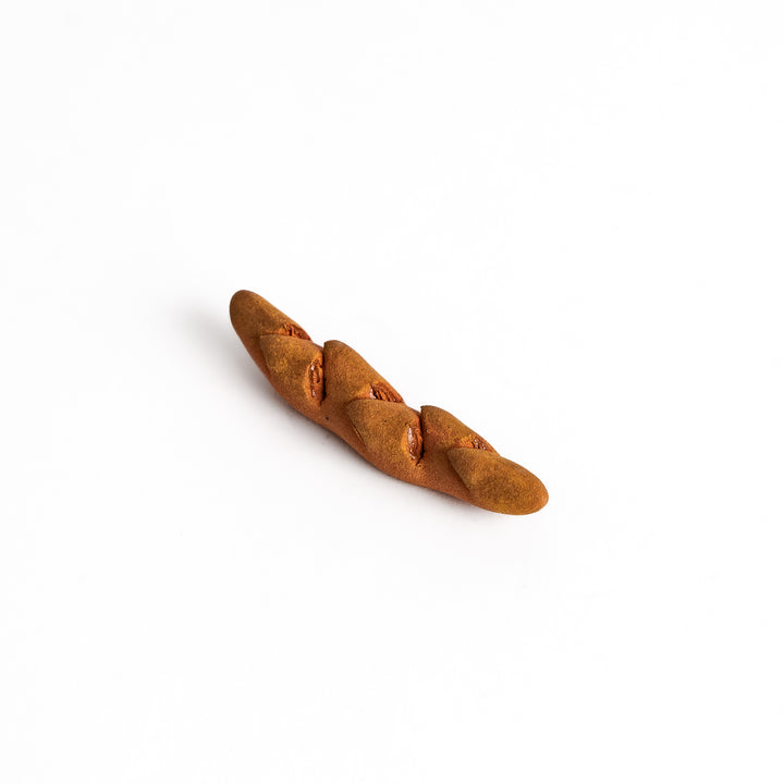 Epi Bread Chopstick Rest shaped like a baguette with intricate details and a warm brown finish, perfect for adding charm to your table setting.