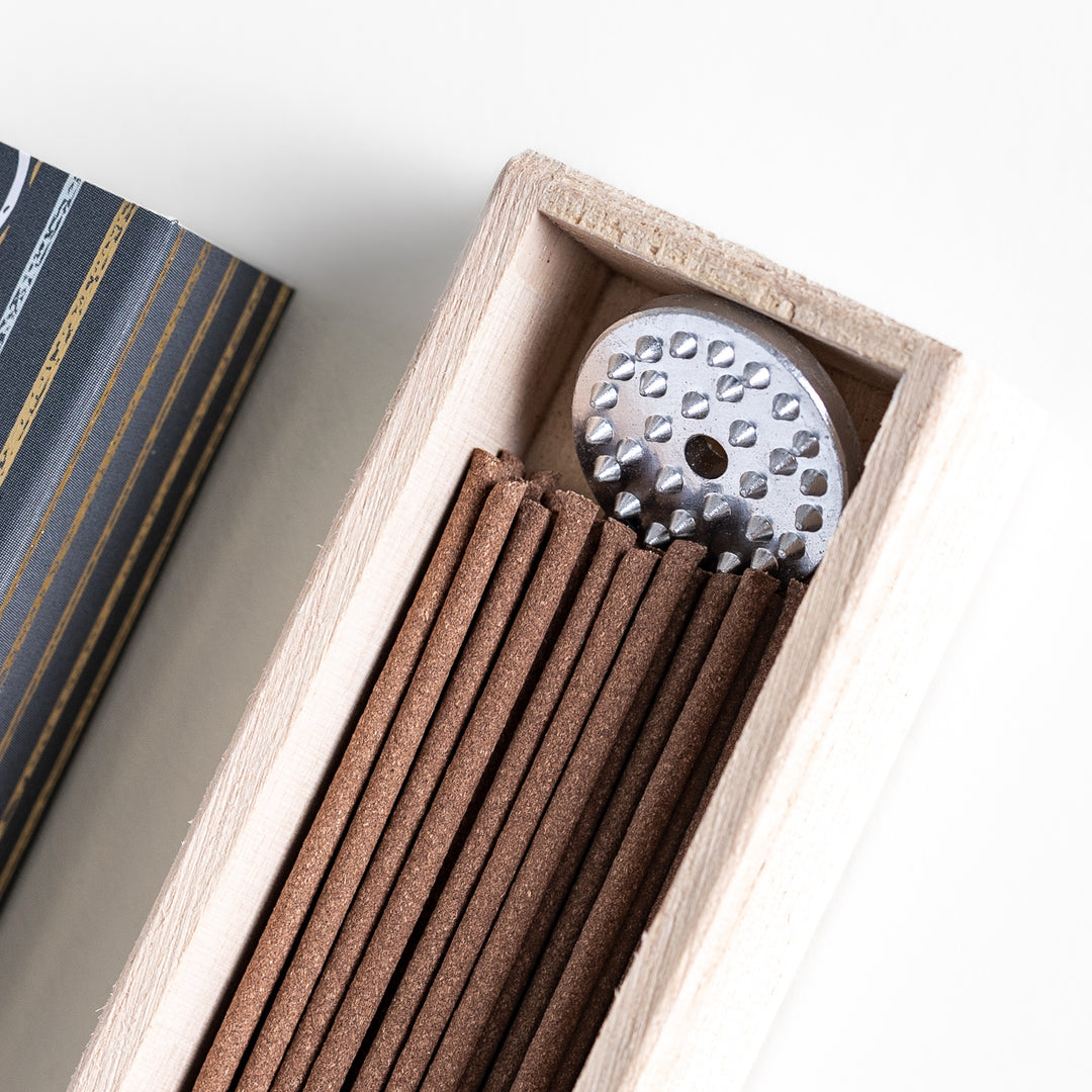 Ethereal Agarwood Incense in a light wooden box with warm brown sticks, elegantly packaged in a deep black design featuring white circular patterns, evoking a rich and meditative agarwood aroma.