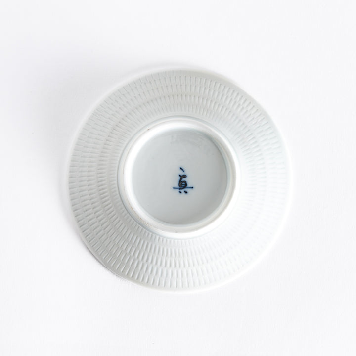 The bottom of the blue dessert plate, featuring a white smooth base with a delicate finish.