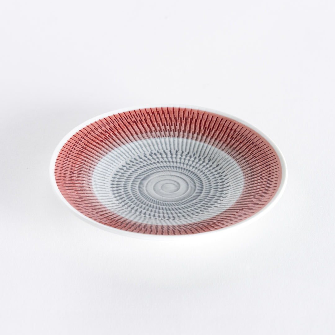 Red dessert plate with vivid spiral-striped patterns, viewed from a slight angle.