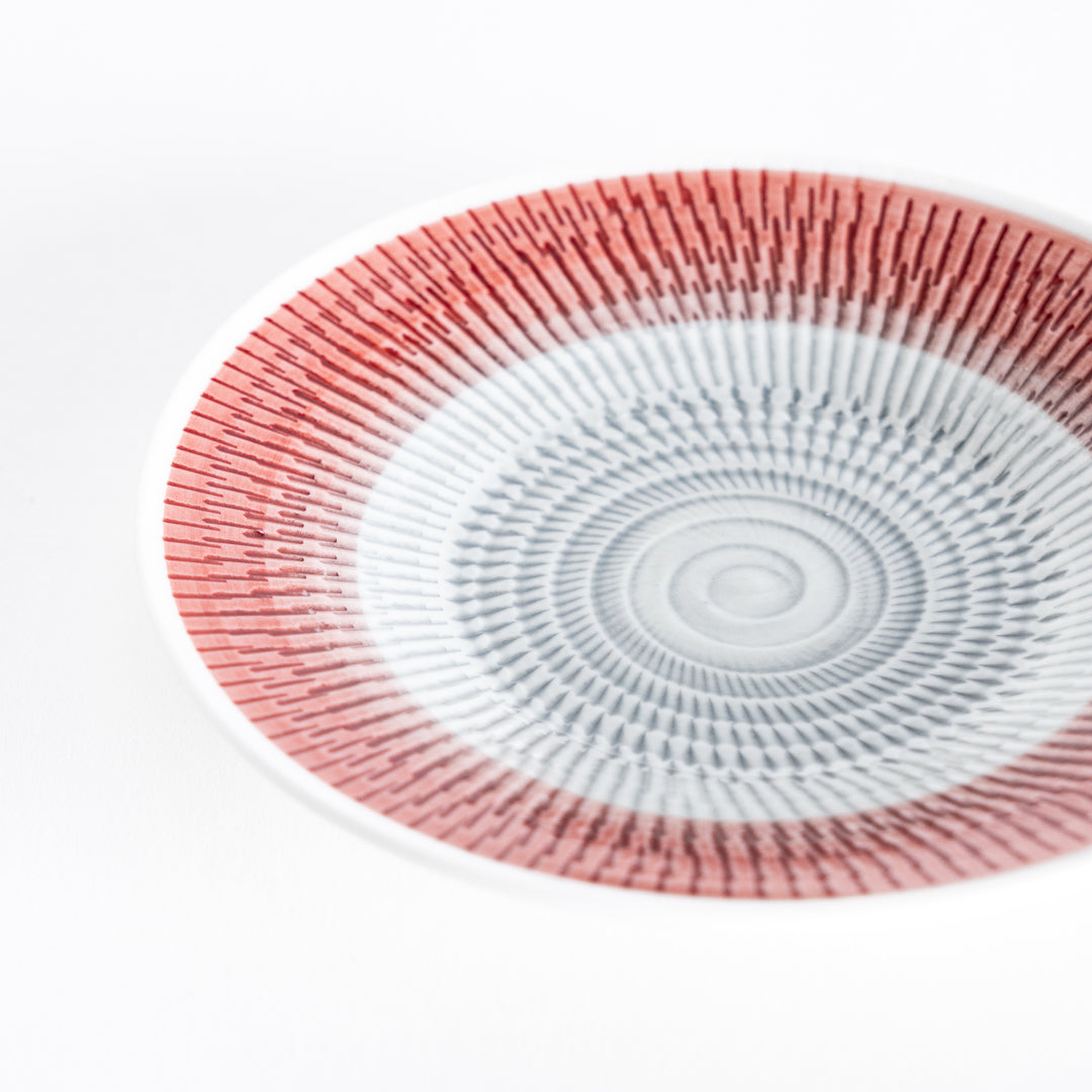 Close-up of the red dessert plate, highlighting its bold and intricate spiral-striped pattern.