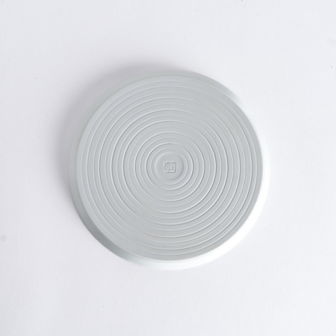 Bottom view of the plate, revealing a clean white surface with a small maker’s mark at the center.